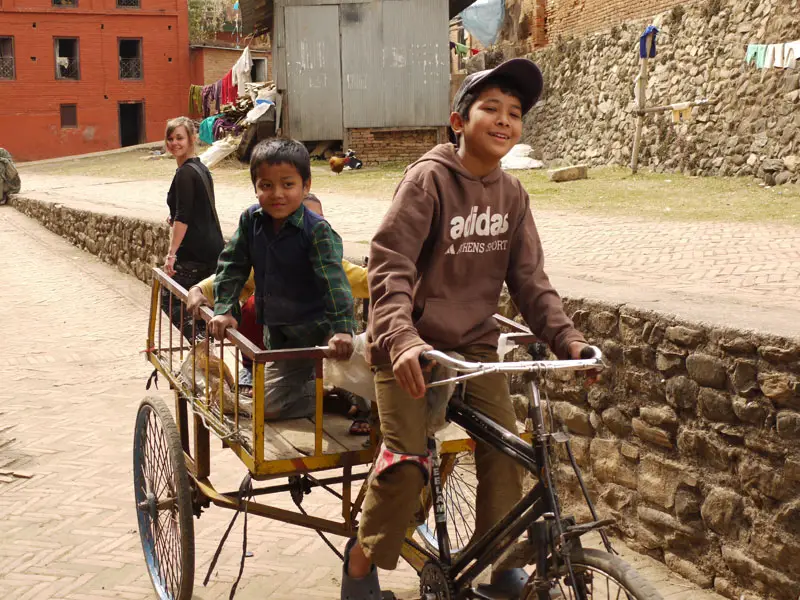Friendly local kids cycling by in Panauti, Nepal