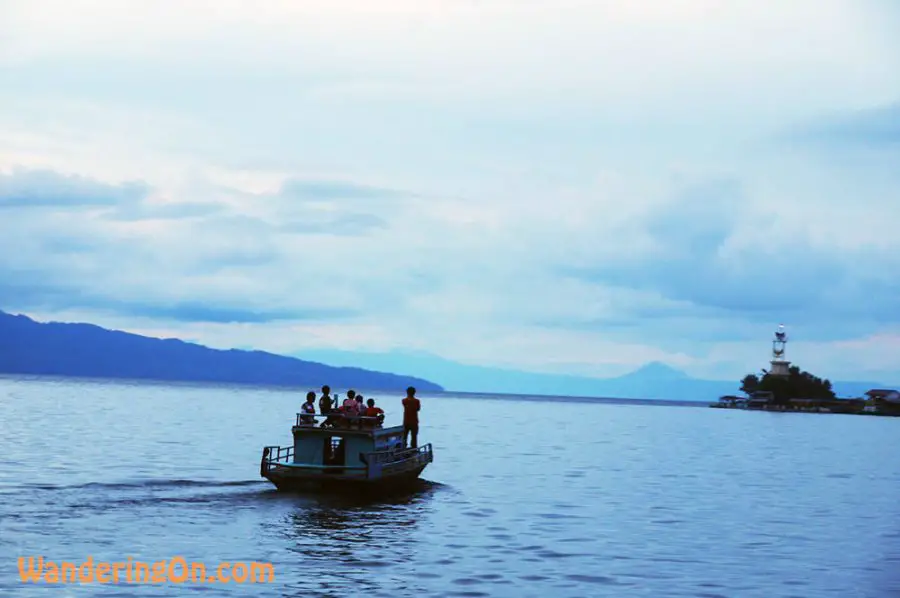 Locals head off across the placid waters of Lake Toba at dusk