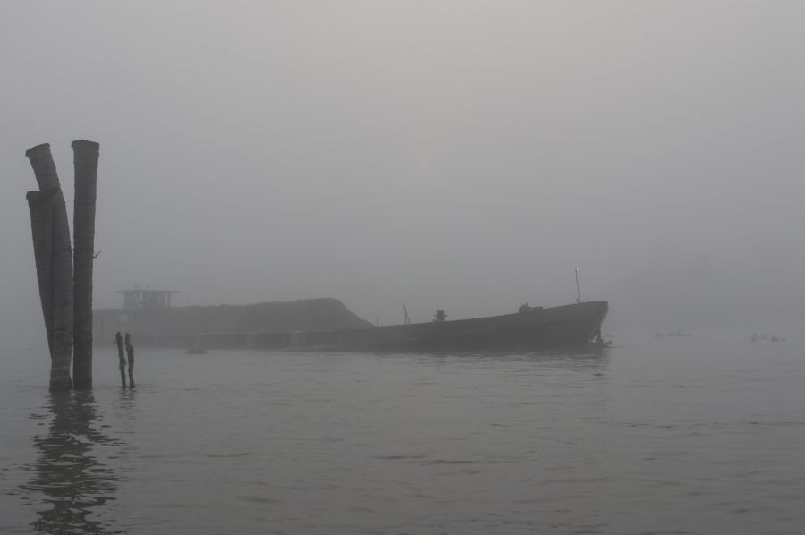 Cargo boat coming through the morning fog before dawn on the Mekong Delta