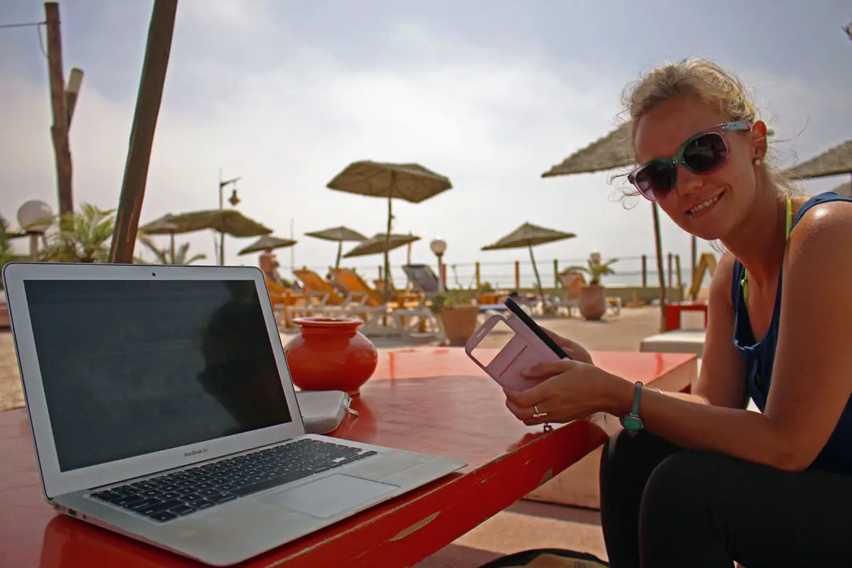 How we afford to travel full-time, Working on our laptops at the beach in Morocco
