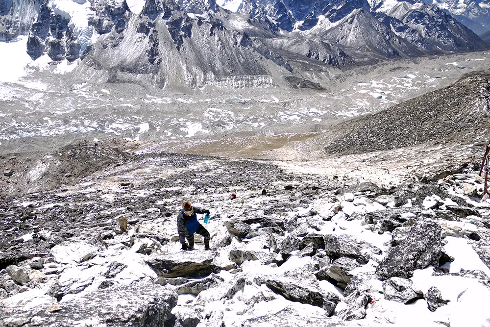 Noelle clambering over rocky terrain on the trail on the Everest Base Camp Trek independently self guided