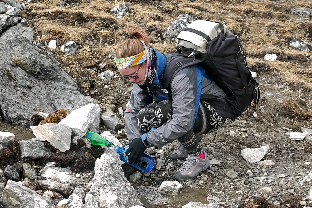 Noelle refilling her water bottle from a stream in the Himalayas 